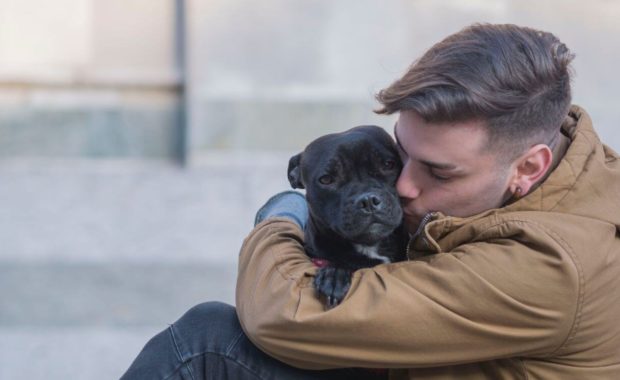 man hugging dog pet